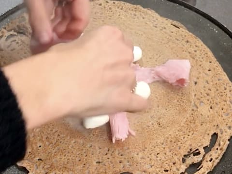 Ajout de morceaux de jambon blanc sur la galette qui cuit sur la crêpière électrique