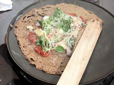 Un côté de la galette est plié avec la spatule en bois