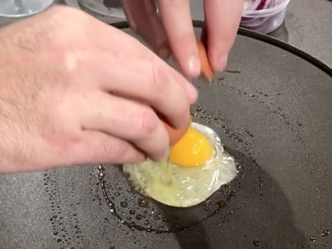 Un œuf est cassé au centre de la crêpière électrique