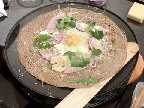 La spatule à crêpes en bois est glissée sous la galette qui est sur la crêpière électrique