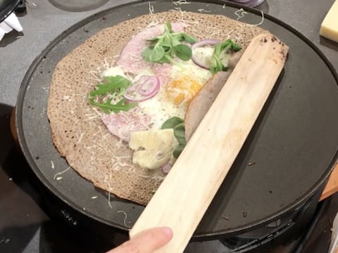 Un côté de la galette est plié avec la spatule en bois