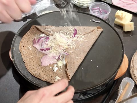 Ajout d'un peu d'emmental râpé sur la galette qui cuit sur la crêpière