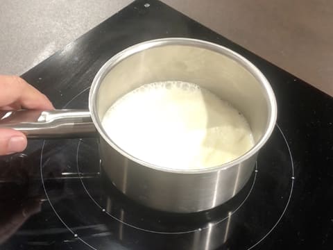 La crème fleurette est en train de chauffer dans la casserole posée sur la plaque de cuisson