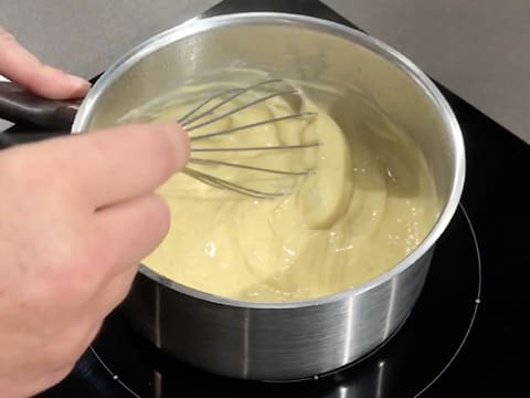 Obtention d'une crème qui est en train d'être fouettée, dans la casserole qui est sur la plaque de cuisson