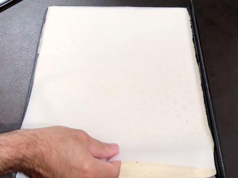 L'abaisse de pâte feuilletée est recouverte d'une feuille de papier sulfurisé