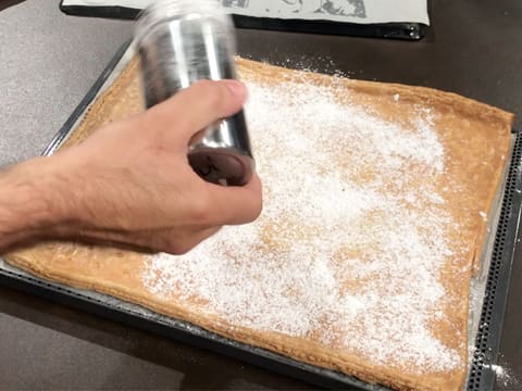 Du sucre glace est saupoudré sur la pâte feuilletée cuite et dorée