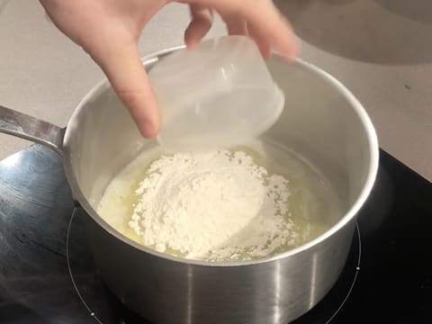 Ajout de la farine sur le beurre fondu dans la casserole qui se trouve sur la plaque de cuisson