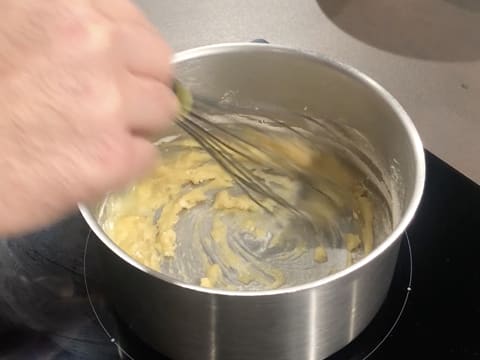 Le beurre et la farine sont mélangés au fouet dans la casserole qui est placée sur la plaque de cuisson