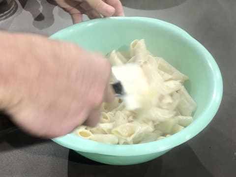 Mélange des pâtes cuites dans la sauce béchamel à l'aide de la spatule maryse, dans le cul de poule