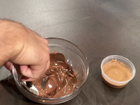 Mélange du chocolat au lait fondu dans le saladier en verre à l'aide de la spatule maryse