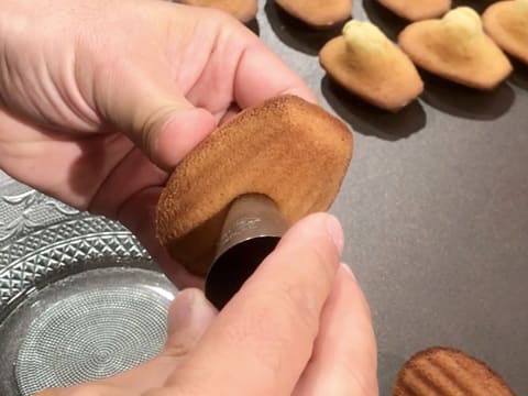 Le dessous d'une madeleine est perforé à l'aide d'une douille en inox