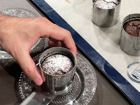 À l'aide d'une spatule métallique coudée, un mi-cuit au chocolat est déposé sur un plat de service