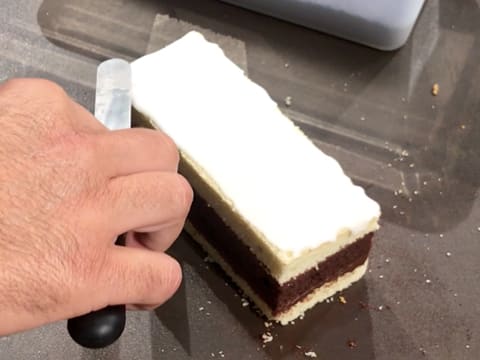 À l'aide de la mini spatule coudée, le glaçage au sucre est étalé de façon régulière sur toute la surface de l'entremets