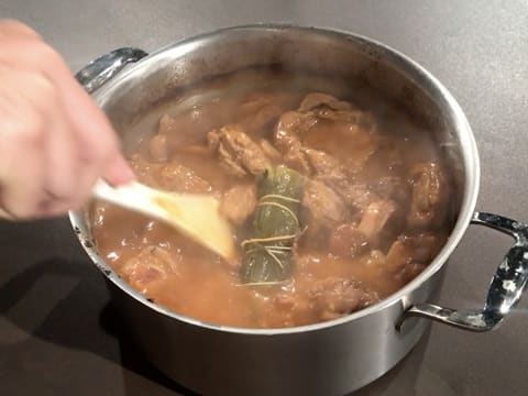 Mélange de l'osso buco dans le faitout à l'aide d'une spatule