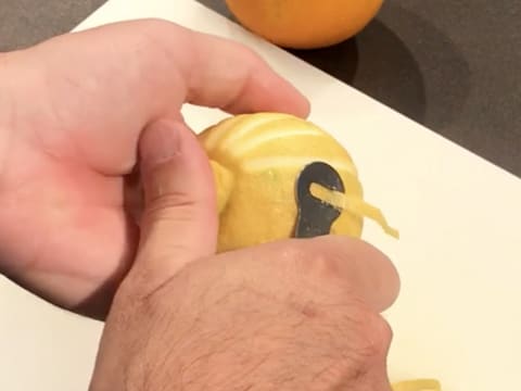 Un zeste sur deux est prélevé d'un citron à l'aide d'un canneleur