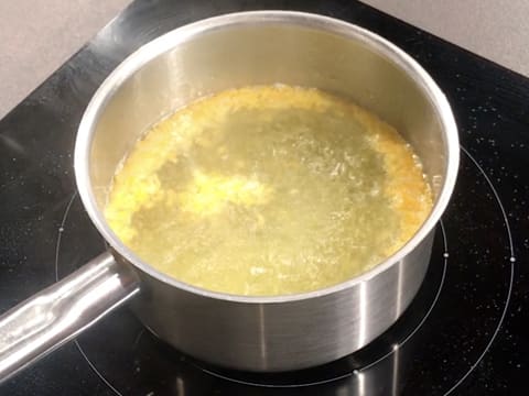 L'eau dans la casserole qui contient les zestes d'orange et de citron émincés, est en ébullition