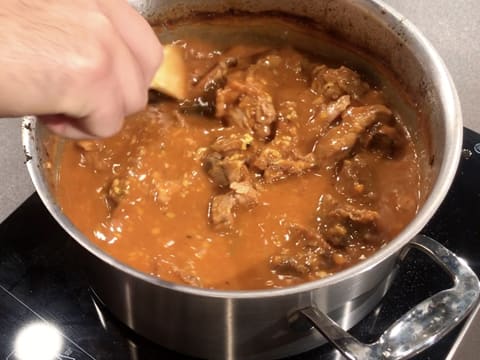 L'osso buco est mélangé à l'aide d'une spatule dans le grand faitout