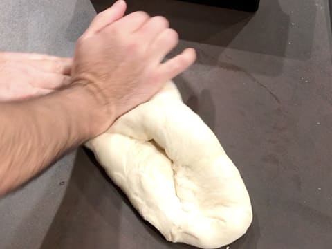 La pâte à pain de mie est disposée en long et rabattue sur elle-même, sur le plan de travail, avec la paume de la main droite