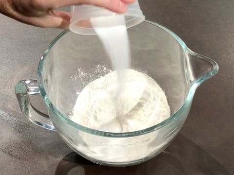 Ajout du sel fin sur le sucre en poudre et la farine, dans la cuve du batteur