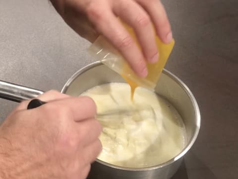 La purée de mangue est versée dans le lait dans la casserole