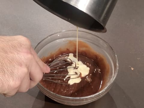 Ajout du restant de lait concentré et de sirop de glucose sur le chocolat fondu dans le saladier en verre