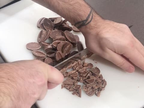 Les fèves de chocolat au lait et au caramel sont hachées au couteau sur une planche à découper