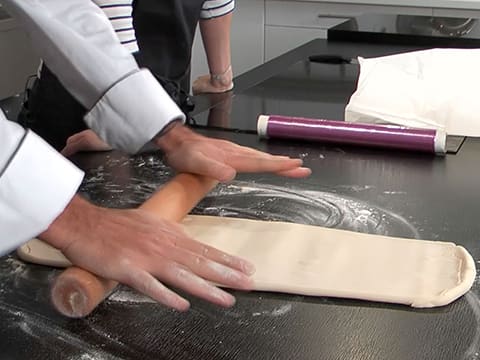 La pâte est abaissée dans la longueur sur le plan de travail fariné à l'aide du rouleau à pâtisserie