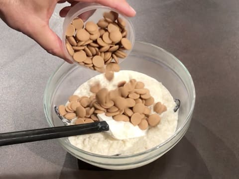 Les pistoles de chocolat Zéphyr caramel sont versées sur le riz au lait dans le saladier