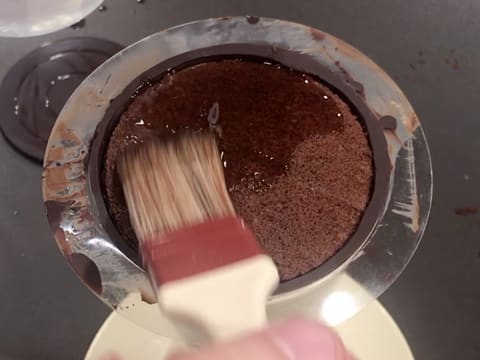 Punchage du biscuit chocolat qui se trouve dans le cône en chocolat, à l'aide d'un pinceau pâtissier