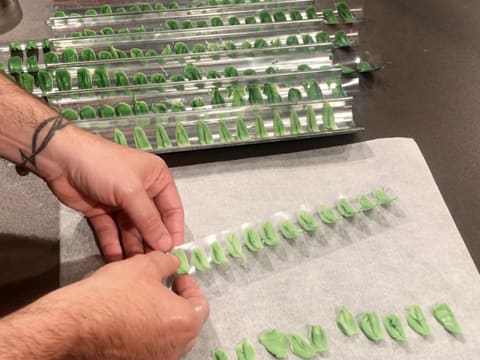 Démoulages des feuilles en chocolat vert clair sur une feuille de papier sulfurisé