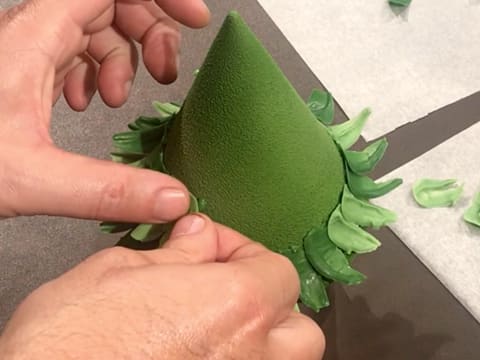 Des feuilles en chocolat vert sont collées sur les gouttes de chocolat vert sur le sapin en chocolat