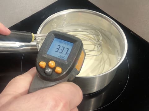 Prise de la température de la préparation à base de fromage blanc dans la casserole, à l'aide d'un thermomètre à visée laser qui affiche 33,7°C