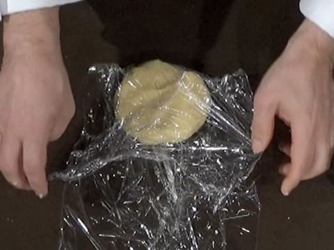 La pâte sablée est enveloppée dans la feuille de papier film, sur le plan de travail