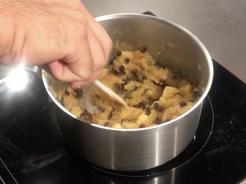La compote de pommes est en train de cuire dans la casserole tout en étant mélangée