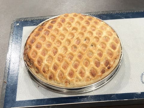 Obtention de la tarte normande aux pommes qui est cuite et dorée posée sur la plaque à pâtisserie recouverte d'une toile silicone