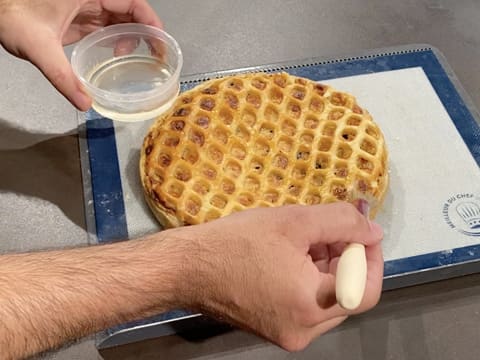 Du nappage miroir neutre fondu est appliqué sur toute la surface de la tarte normande aux pommes avec le pinceau pâtissier