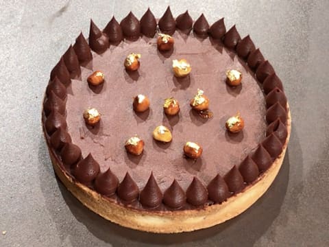 Obtention de la tarte piémontaise au chocolat décorée de noisettes caramélisées et d'une pointe de feuille d'or