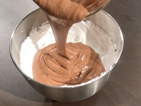 La préparation au chocolat est versée sur la meringue italienne qui est dans la cuve du batteur