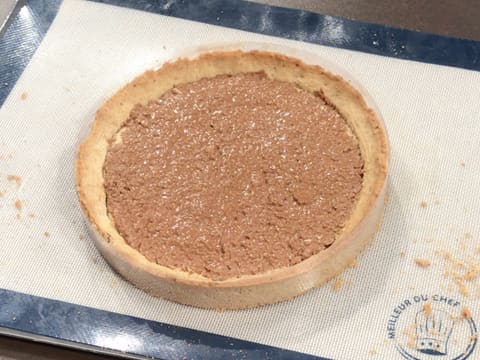 Le fond de tarte cuit recouvert de croustillant noix de pécan est sur le tapis de cuisson en silicone