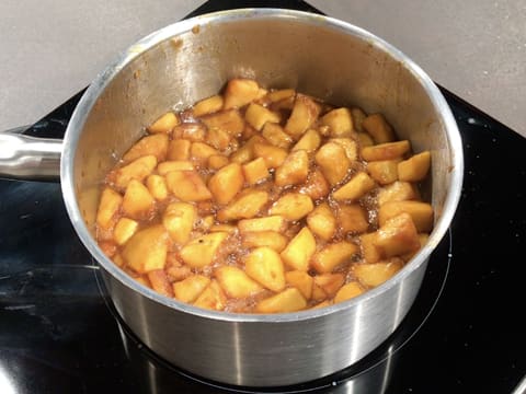 Les pommes et le caramel sont en train de cuire à petit frémissement dans la casserole