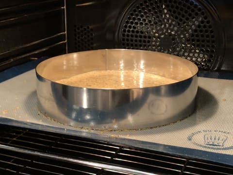 Le cercle à mousse contenant la préparation de moelleux aux noisettes et le disque de streusel est placé dans le four