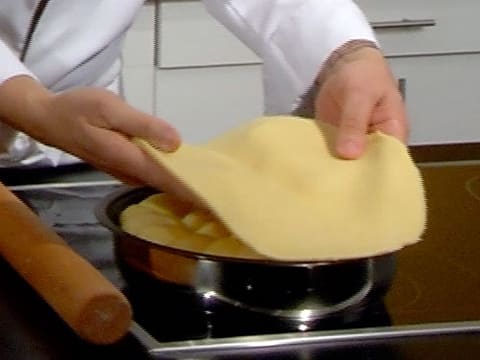 Le disque de pâte brisée est déposé sur les pommes qui sont dans le moule à tarte tatin