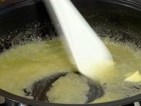 Le sucre en poudre et le beurre qui est presque entièrement fondu dans le moule à tarte tatin sont mélangés ensemble à l'aide de la spatule