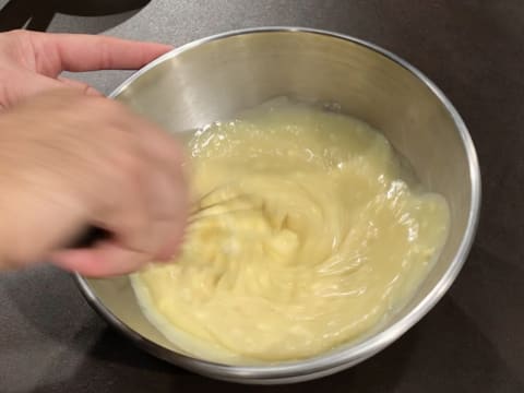 La crème au chocolat blanc est mélangée au fouet dans le cul de poule qui est posé sur le plan de travail