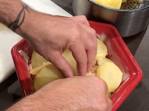 Les rondelles de pommes de terre sont rangées harmonieusement, en une couche régulière, sur les lardons et oignons cuits, dans le plat à gratin