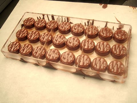 Premium Photo  Top view of squeezing filling of salted caramel cream from  confectionery bag into candy molds for preparing handmade chocolate pralines