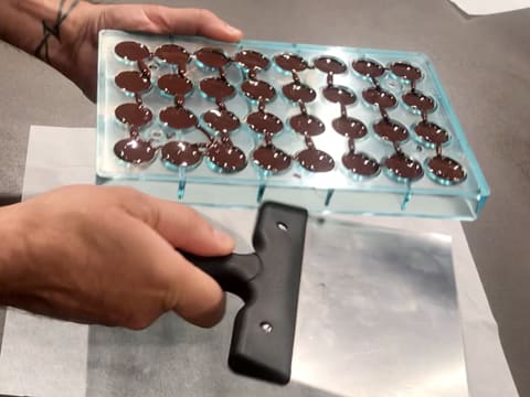 Tap the sides of the half sphere chocolate mould with a spatula