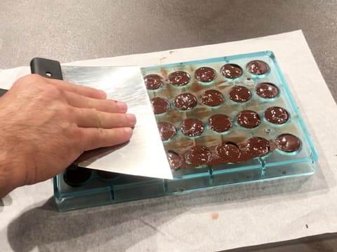 Even the surface of the mould with a chocolate spatula