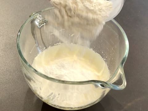 The sifted ingredients are poured over the beaten eggs in the bowl