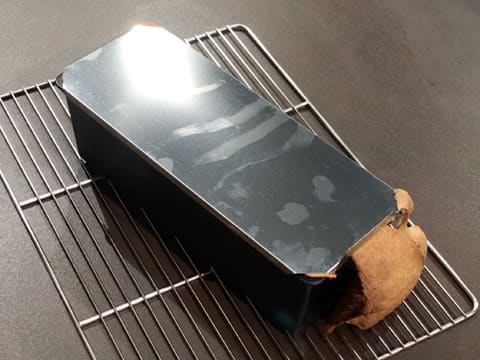 The bread pan is on a rack on the kitchen workbench